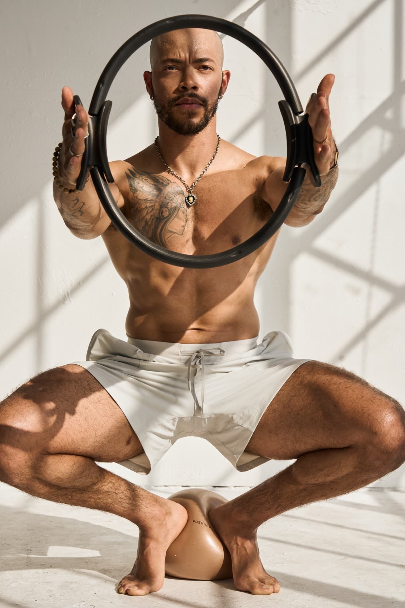 Greg seated, holding the Pilates ring up to frame his face